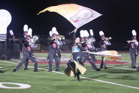As she twirls across the field, junior Kari Koerner waves her flags while the band plays behind her. The Silver Falcons performed during halftime at the Homecoming football game on Sept. 30.