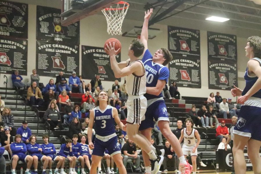 Jumping up for a layup, junior Roman Gilbert takes a shot as Northwests Jake Randazzo attempts to block it. The Falcons defeated the Lions at home 67-38 on Jan. 12.