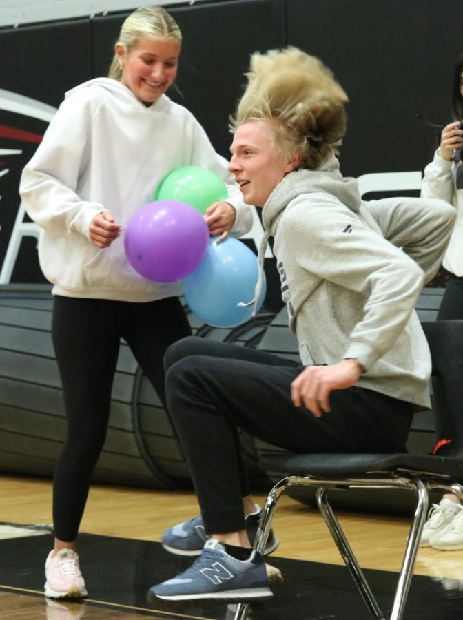 As senior Brayden Timm leaps on the chair and pops the balloon, junior Leah Mehrhoff stands by ready to place another. The seniors won the game that was held at the winter pep rally on Feb. 10.