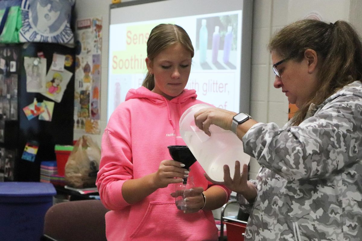 With help from health teacher Christine Hohlt, sophomore Leila Miller creates a sensory bottle during wellness lab on Oct. 10. A variety of activities  were offered by teachers like Hohlt the week of Oct. 9.