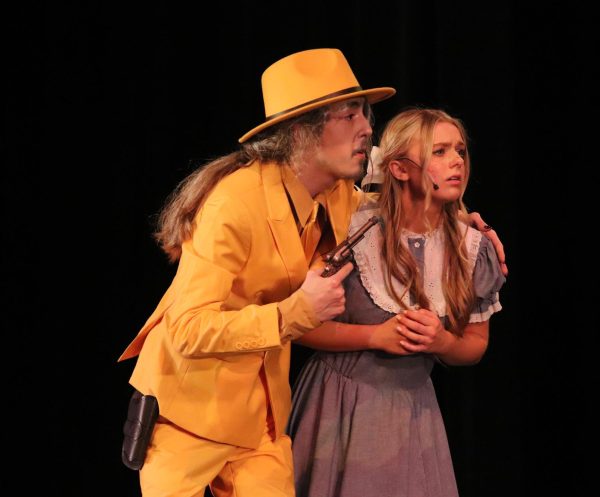 Demanding the water, the Man in the Yellow Suit (junior Oliver Stratton) holds Winnie (junior Faith Roberts) at gun point. The musical took place March 7-9.