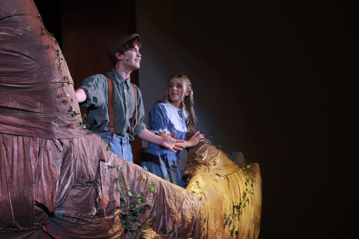 As he climbs to the top of a tree, Jesse Tuck (sophomore Jackson Schertzer) shows Winnie Foster (junior Faith Roberts)  his love for adventure with Top of the World.
