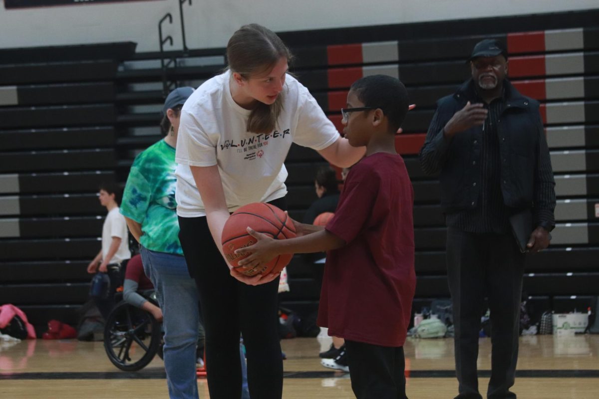 Handing him a ball, senior Alexis Lieberman pointsher buddy in the direction of the basket. The Special Olympics took place in the gym on March 15.
