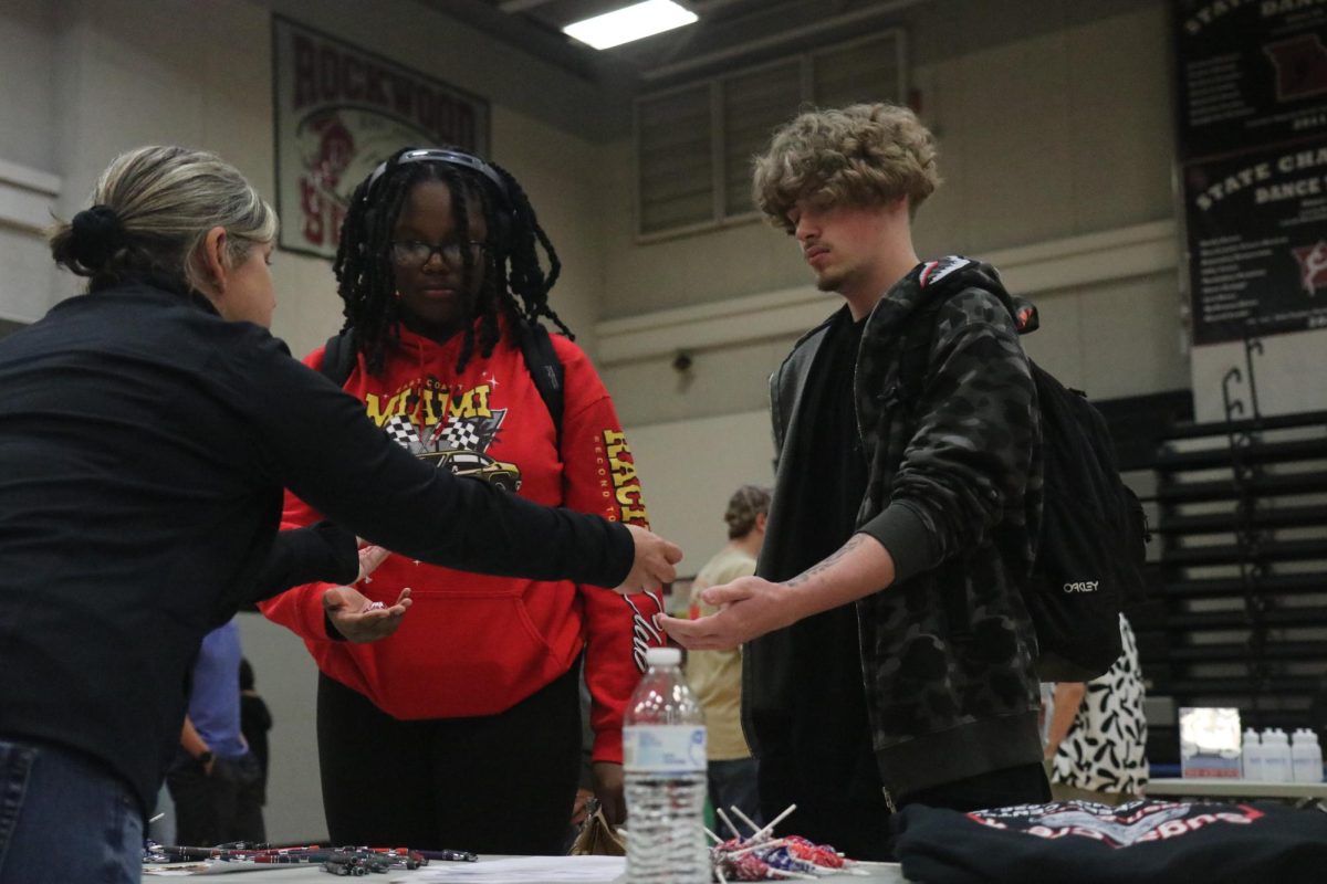 Juniors Emily Robinson and Joshua Cross receive candy from a business at the job fair. All of the businesses in attendance at the event were looking for new employees.  