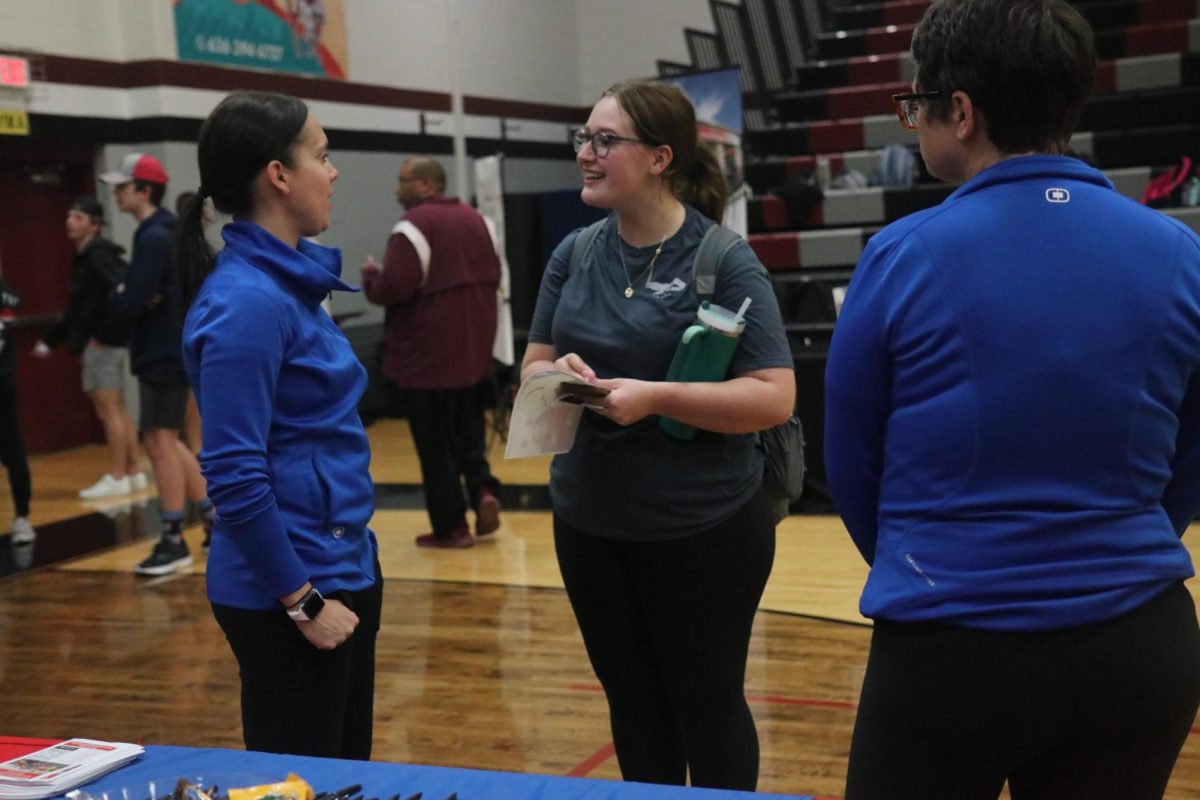 Junior Vivian Ricci speaks to Olympia gymnastics employees about a position.  “[The job fair] was helpful to learn what other options I had and what [employers] were looking for. It was super helpful for me to narrow down my job search,” Ricci said. 