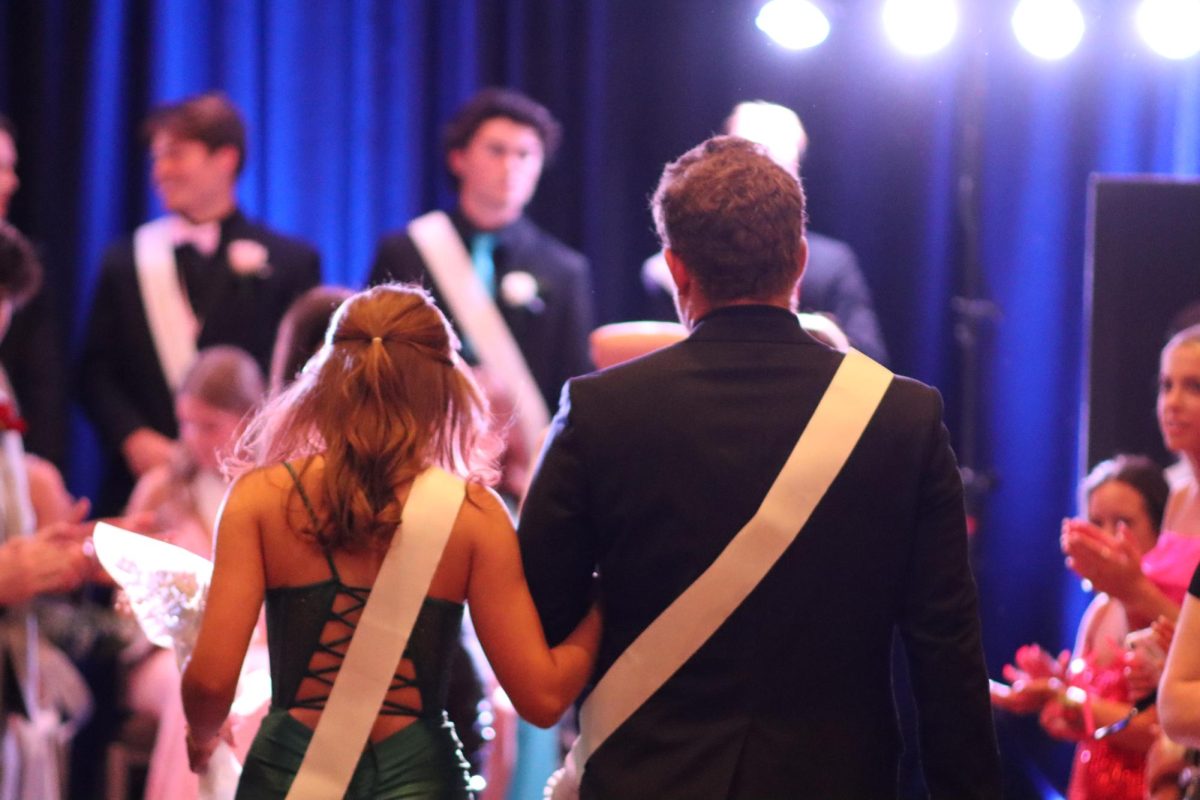 Walking down an aisle of people, seniors Ali Sandler and Grant Gibson loop arms. The two were members of the Prom Court on April 20 at the DoubleTree in Chesterfield.
