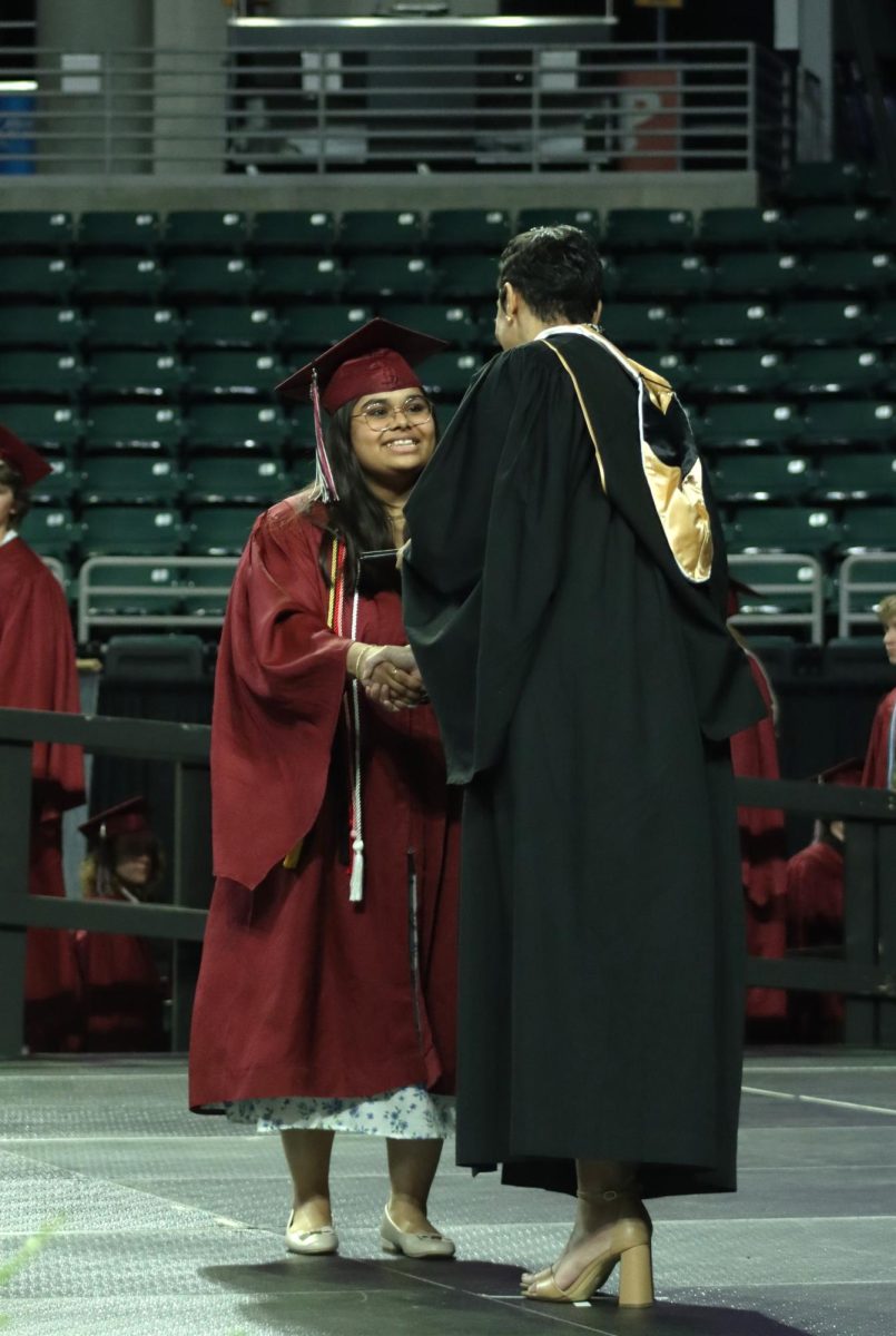 Graduate Muskan Patel shakes the hand of board member Jessica Clark as she is presented her diploma. 
