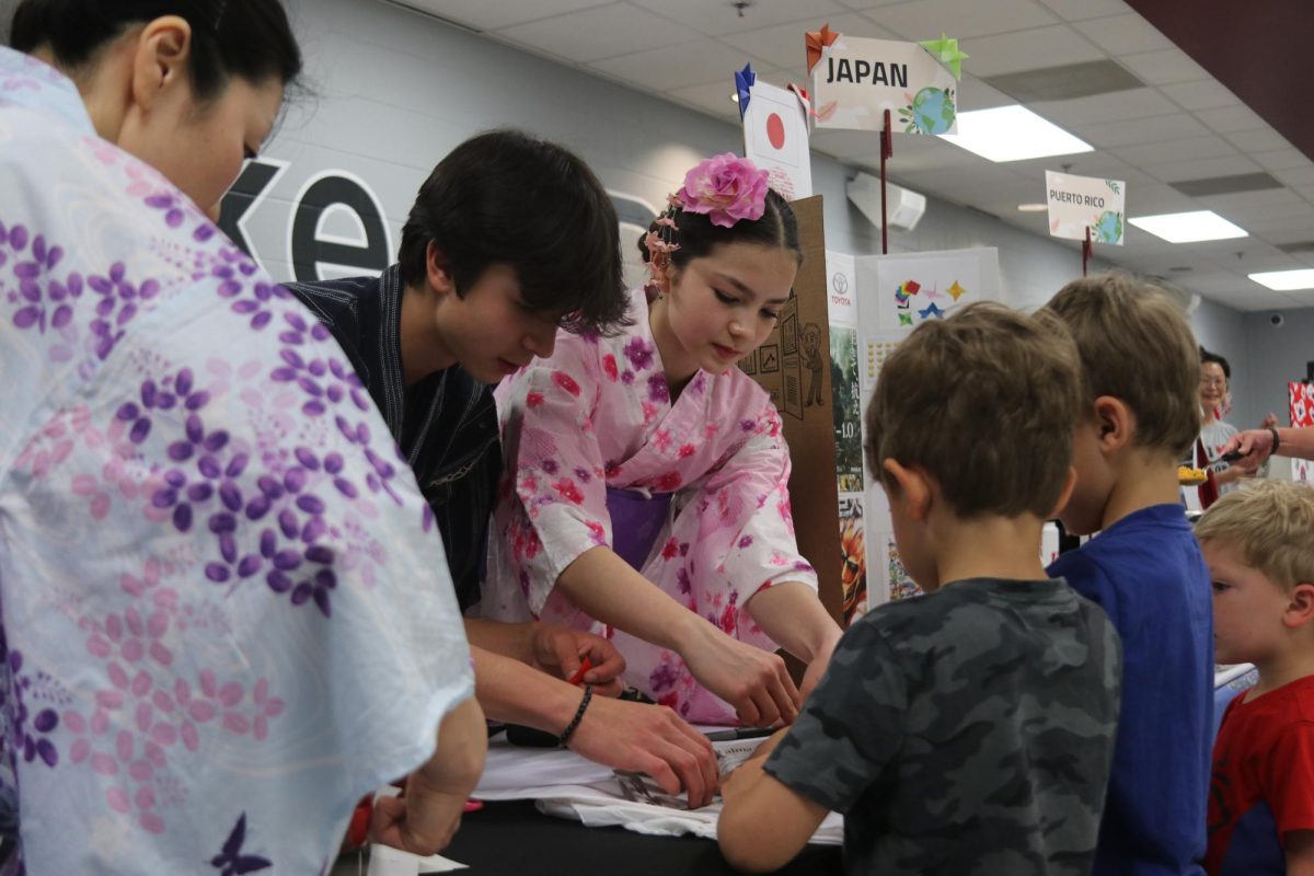 At their Japan table, sophmore Hiroki Fingerhut and his sister Amane, a seventh grader at Rockwood South Middle School, teach kids how to create origami at the fair. Intercultural night took place at RSMS on May 1.