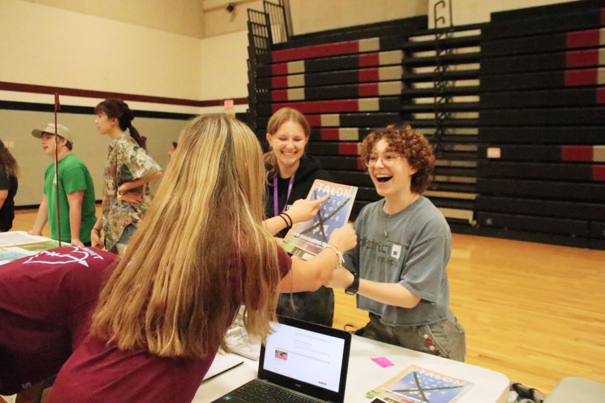 Promoting the Talon, sophomore Skylar Holtgrewe and senior Abbott Lackey talk to junior Julia Shiner, a potential new staff member in the Main Gym. On Sep. 5, the Summit Student Council hosted an activities fair where students could discover new ways to become involved in the school.
