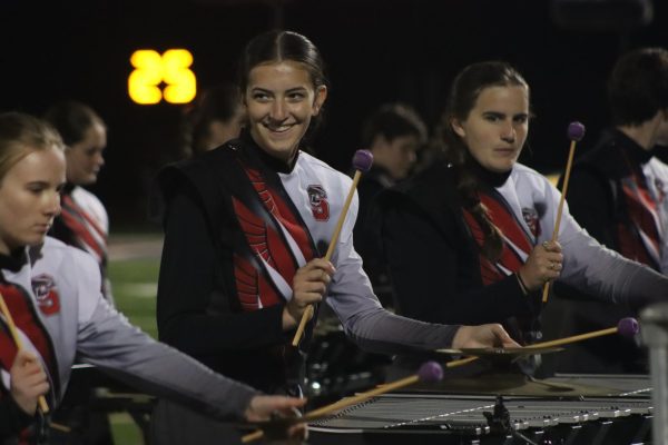 Playing the vibraphone, sophomore Lucy Vanderheyden smiles at her fellow front ensemble members during the halftime show. The band performed their show 'Beyond the Sidewalk' at the football game on Oct. 18.