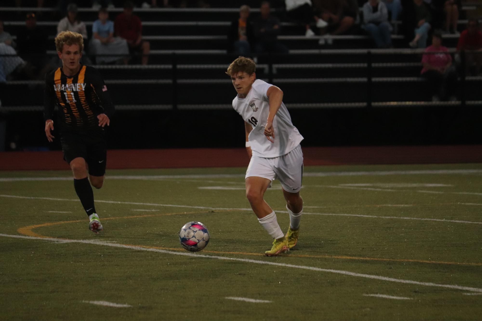 Junior Wyatt Oetjen runs towards the ball to make a pass as Shane Farrow (11), of Vianney, attempts to make a steal.