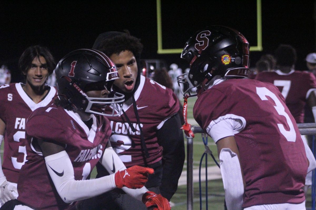 Seniors Makiye Hughes (2) and Kaloep Young (1) hype up junior Jasahn Tiller (3). The Falcons won 59-28 on Oct. 18.