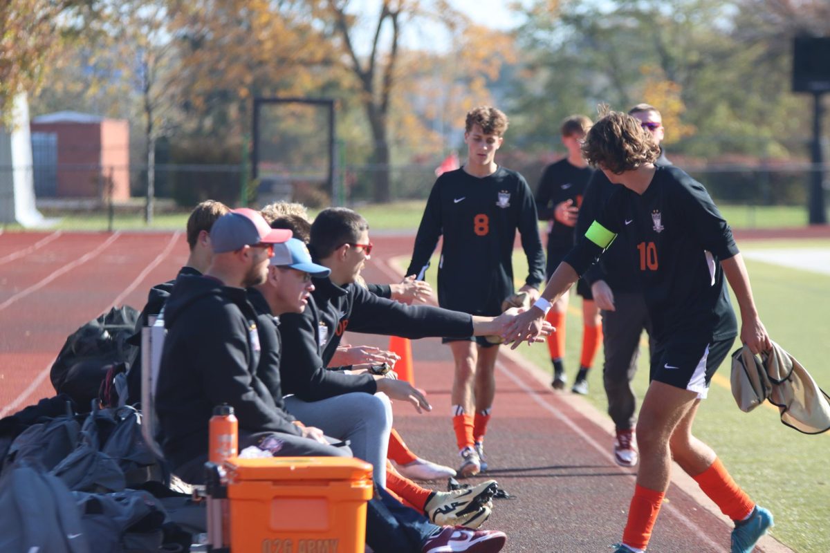 Junior team manager Oliver Puljic high fives junior Jack Steele as Steele comes off the field. Steele, a captain, had one goal for the Falcons, helping them pull out a 4-0 win against Washington High School. 