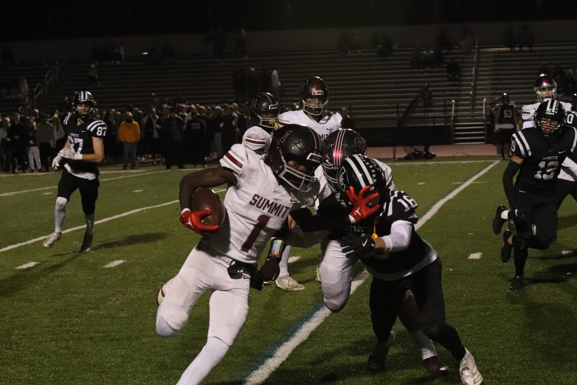 Senior Kaleop Young (1) stiff arms Zachary Toben (16) of Lafayette during a kick off return near the end of the first half. Summit was defeated 49-7 at Lafayette on Nov. 8.