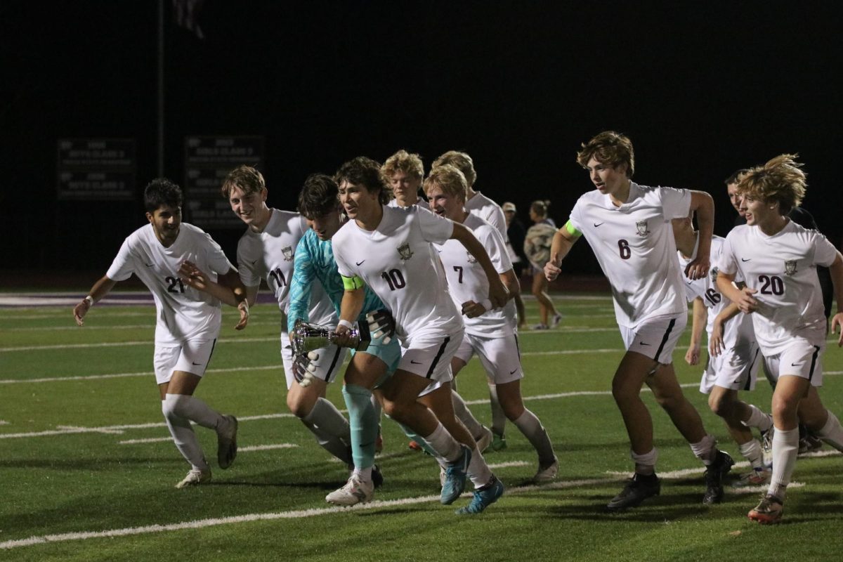 Junior Jack Steele (10) sprints with the trophy in hand as juniors Hamza Ahmad (21), Evan Wade (11), Nick Nusser (2), Gavin Werner (7), Quinn Larocque (16), AJ Touhy (20) and seniors Jack Loeffelman (0) and James Berry (6) follow.