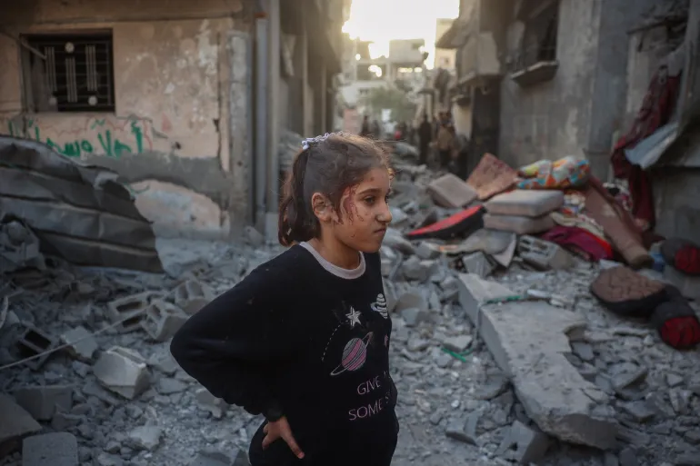 An injured girl stands amid the rubble of a house destroyed in an Israeli attack at the Bureij refugee camp in the central Gaza Strip.