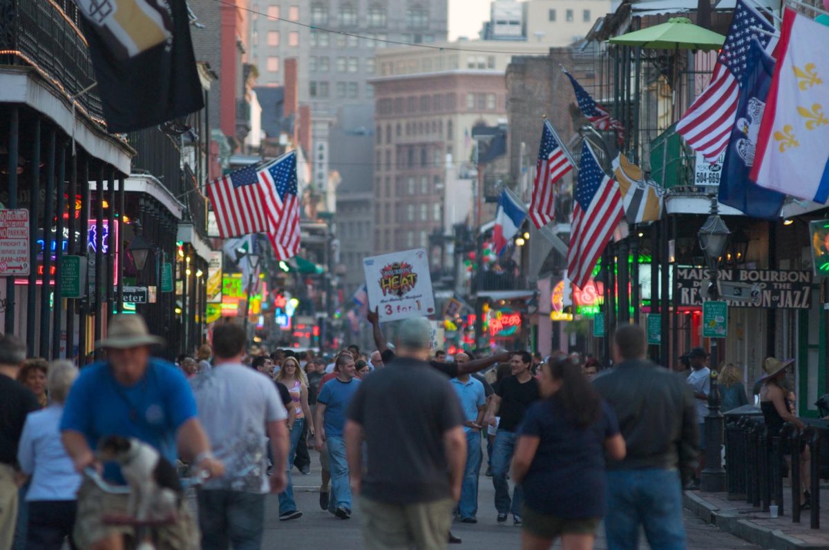 The famous Bourbon Street in New Orleans is crowded with people. Bourbon Street is in the heart of French Quarter, charged with culture, lively music, and decorated with beads and lights.
