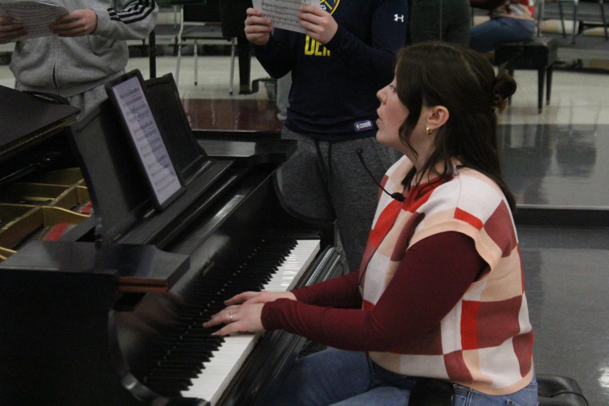 Choir director Gabrielle Pierle teaches a song to boys in Mixed Concert Chorale as they're gathered around her piano. The choir will perform for the first time with Pierle as a director in their MIOS concert on Mar 26.