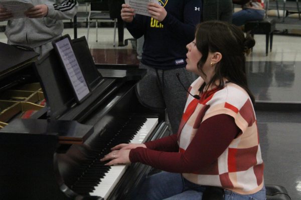 Choir director Gabrielle Pierle teaches a song to boys in Mixed Concert Chorale as they're gathered around her piano. The choirs will perform for the first time with Pierle as a director in their MIOS concert on Mar 26.