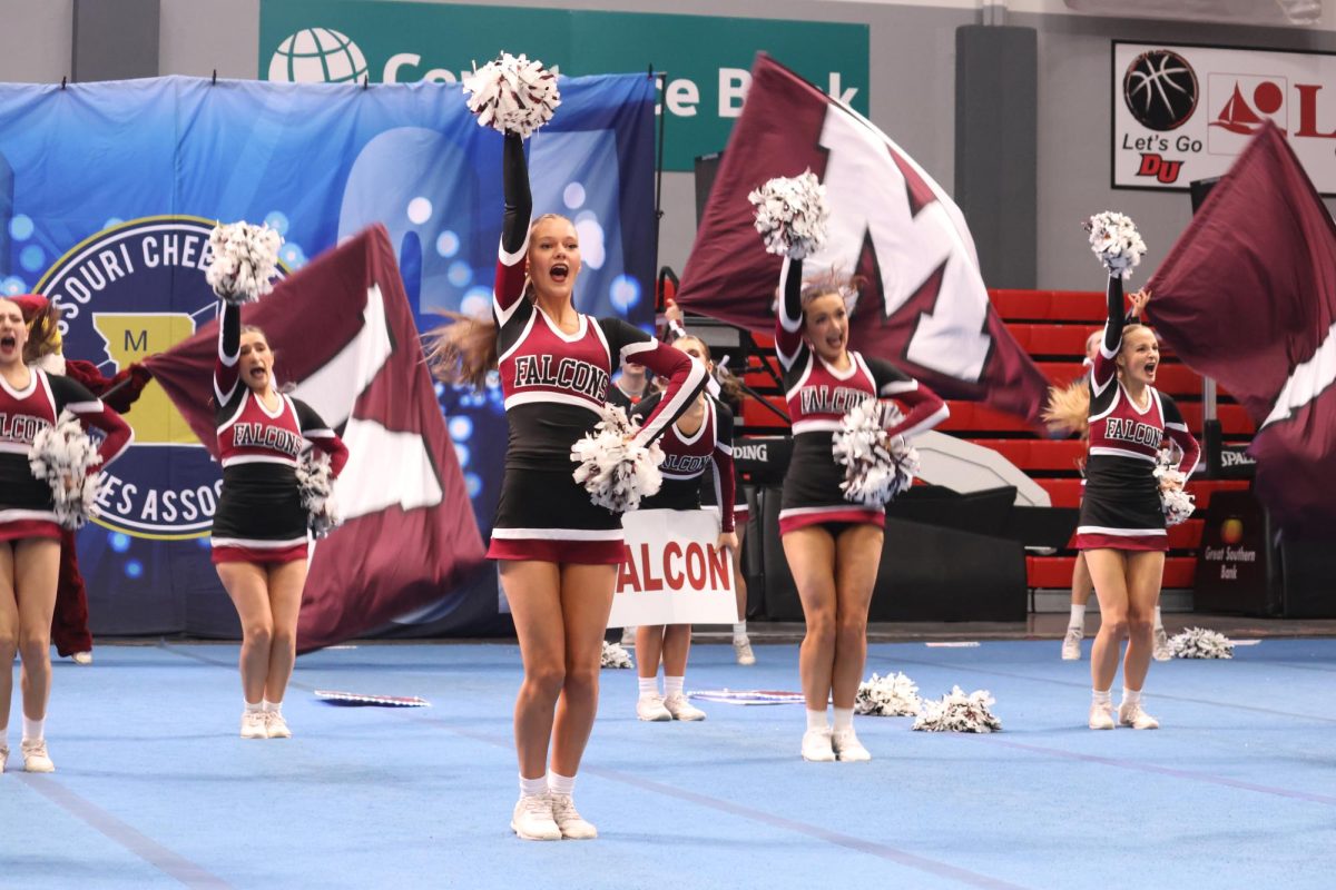 Senior Brice Davis, junior Dana Spray, and senior Keegan Thuet punch their poms in the air during the band chant.
