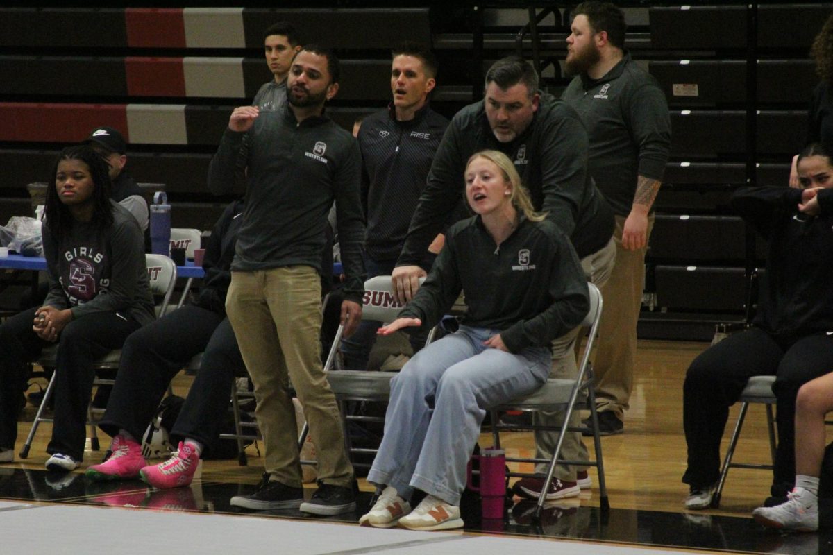 Coaches Sean Torgoley, Jon Bunyard, Kenneth Holmes and alumna Addie Wilhelm (Class of 2022) watch on as Myla Walker struggles with her opponent.