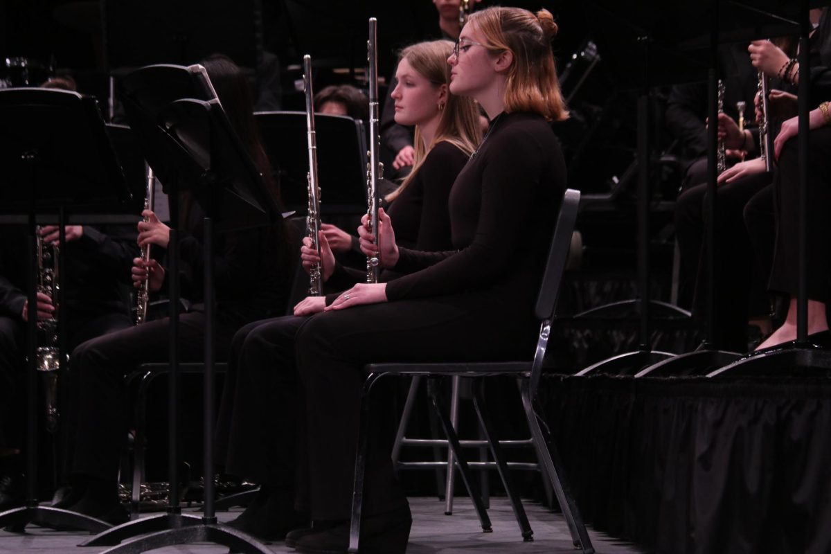 Reading over their music, sophomore Ava Procter and senior Phoenix Honzell prepare to play their flutes during the MMEA Band Concert.