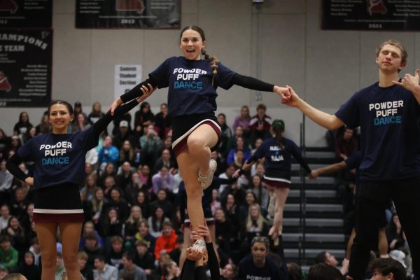 Stunting, sophomore Addie Mueller, and juniors Peyton Siefert and Thomas Reichmuth hold hands as they perform in the Powder Puff routine with the cheer team.