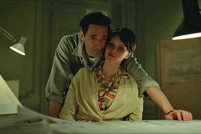 In their home, László Tóth (Adrien Brody) and his wife, Erzsébet Tóth (Felicity Jones)  scan paperwork as they comfort each other. (photo from Vulture)