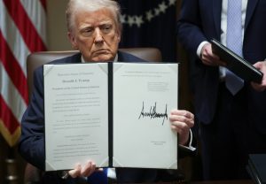 President Trump holds up a signed executive order in the Cabinet Room of the White House on March 25. (photo from Politico)