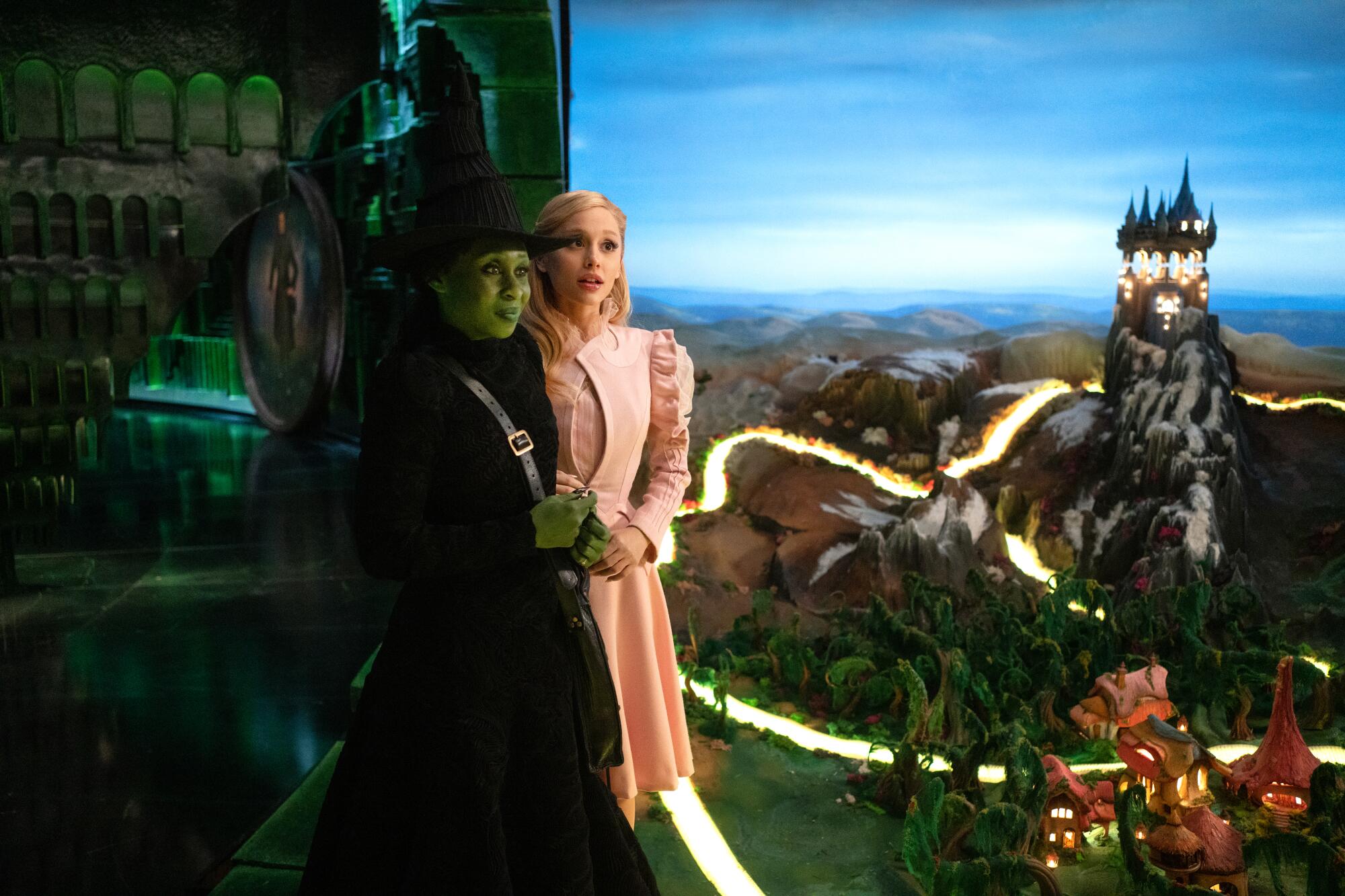 Elphaba (Cynthia Erivo) and Glinda (Ariana Grande) watch as the Wizard of Oz gives his presentation during their visit to the Emerald City. (photo from the Los AngelesTimes)