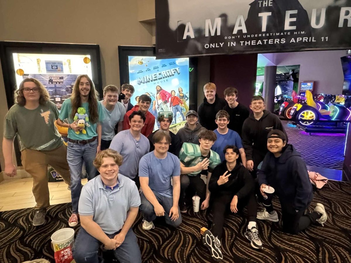 Senior Michael Stimpson poses in front of a Minecraft movie poster with a group of friends at Ronnie's Cinema in Sappington. (photo used with permission from Stimpson)