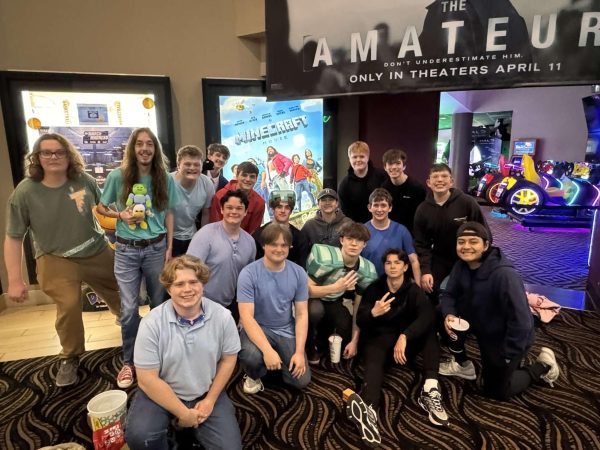 Senior Michael Stimpson poses in front of a Minecraft movie poster with a group of friends at Ronnie's Cinema in Sappington. (photo used with permission from Stimpson)
