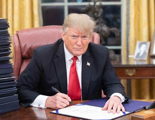 With a stack of many more on his desk, President Trump signs an executive order on Jan. 20. On this day, the president also signed the “America First Trade Policy” memorandum, outlining his ideas for an economy that relies less on foreign products. (photo from Assahifa)