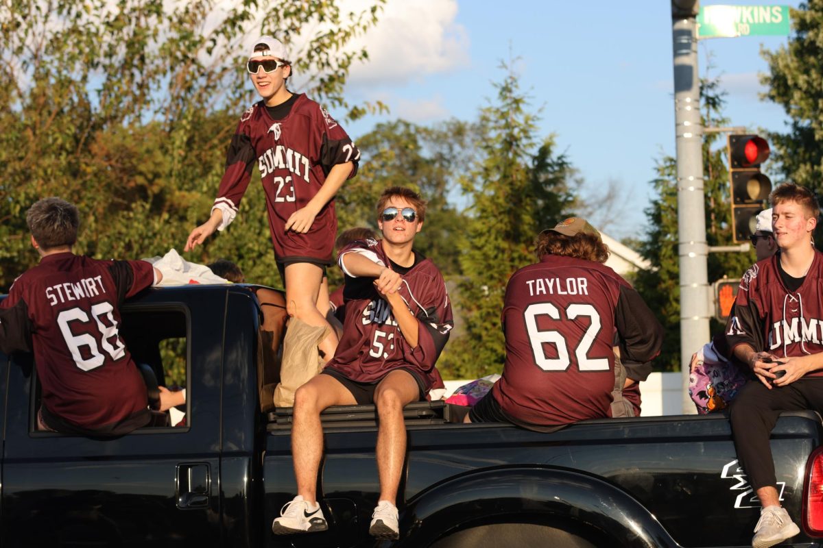 As teammates freshman Tre Stewart (68), sophomore Aiden Anders (23), senior Connor Taylor (62), and junior Brady Jansen ride along in the Rockwood Summit Hockey Club's float, junior Scott Muholland (53) tosses candy to the crowd. The homecoming parade took place on Sept. 19, highlighting various clubs and teams across the school.