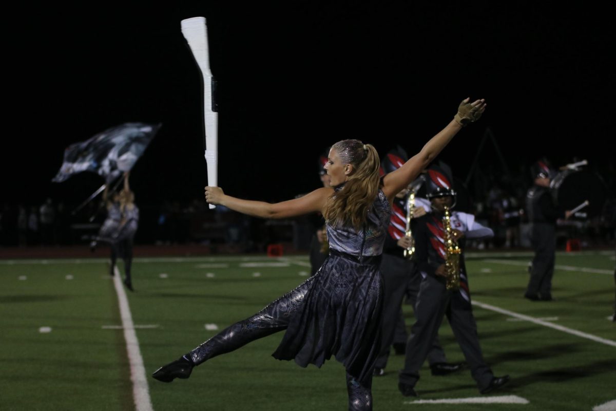 Junior Amelia Otto swings her rifle as she jumps in the air during the Marching Band's show "Luxe." The band performed their first and second movements of the show at the home football game on Sept. 5.
