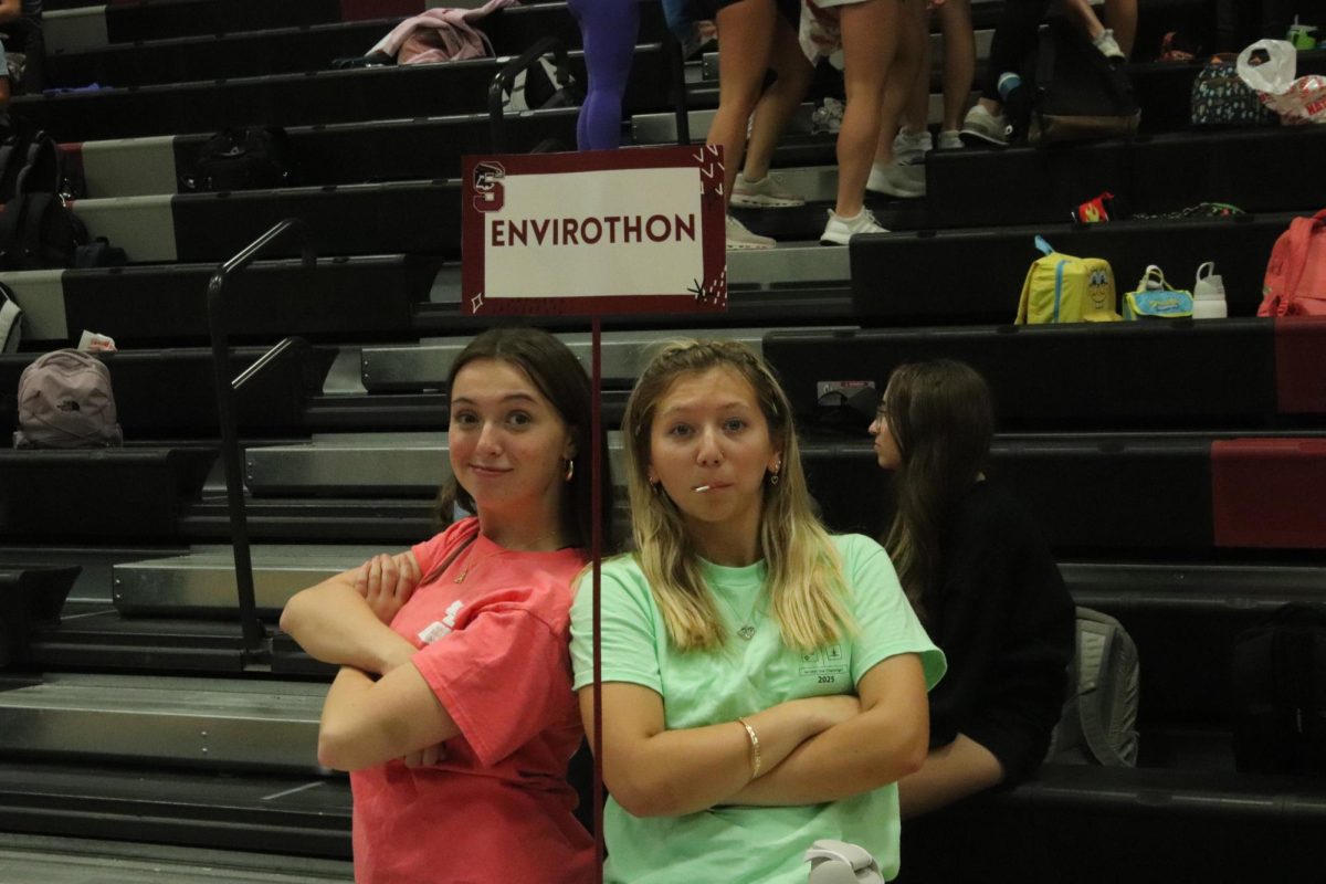 Seniors Annie Jones and Ella Naslund pose with the sign for their Envirothon booth during the Activities Fair. The Activities Fair took place on Sept. 2 in the main gym during second session of AcLab.