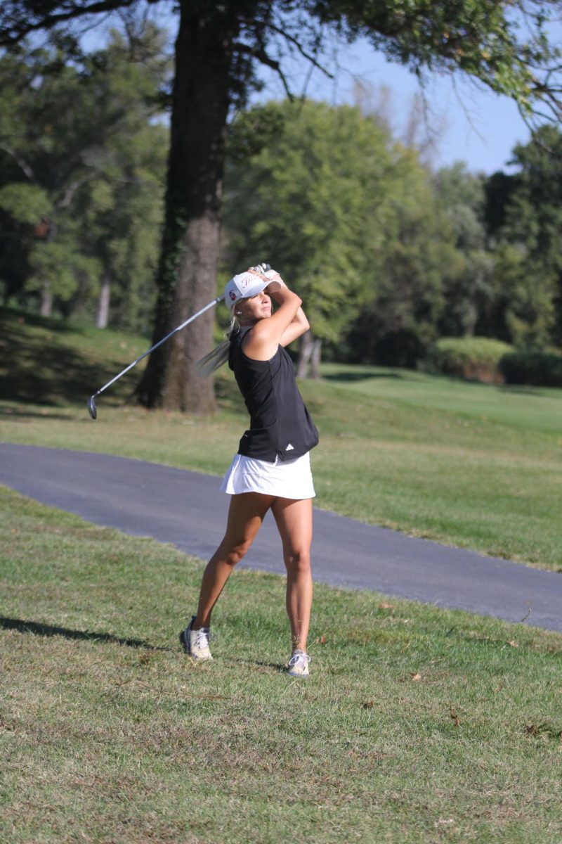 Watching her shot, senior Tallia Brown swings her club.