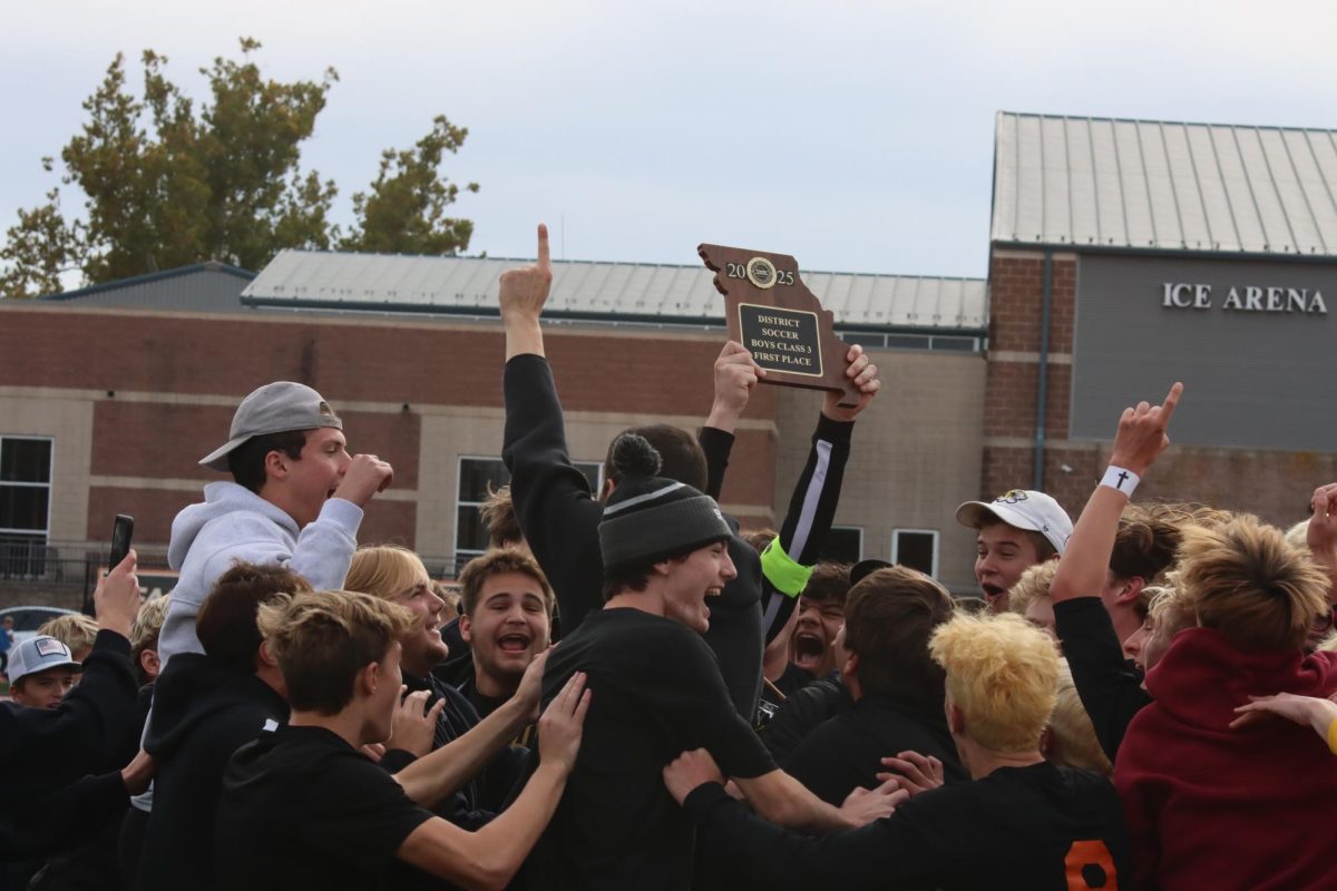 Celebrating their win, Summit students hold the Class 3 District 2 trophy in the air, along with the number one to represent the Falcons’ district win. The boys soccer team faced off with the Webster Groves High School Statesmen in the district final at Hixson Middle School on Nov. 8, ending with a score of 2-1.