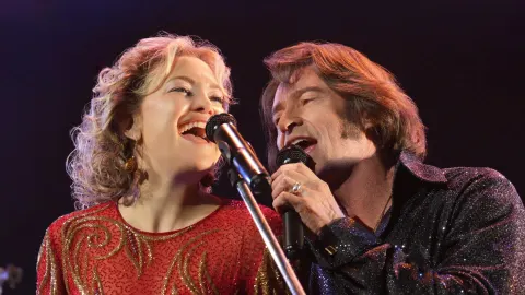 Claire (Kate Hudson) and Mike (Hugh Jackman) sing into microphones during a scene in the film. (photo from The Hollywood Reporter)