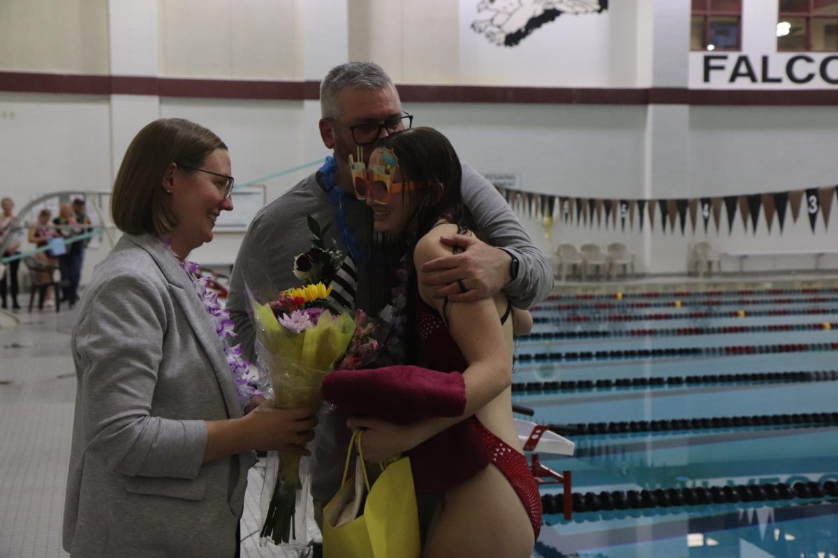 Embracing parents Mandi and Matt, senior Mia Schweigert accepts a bouquet as congratulations during senior night celebrations after the meet. After this meet, the girls were scheduled to participate in three more away meets before the beginning of the Class 1 District 1 Tournament on Feb. 13.