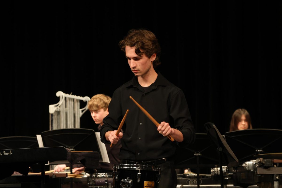Checking his music, senior Michael Charleston plays the snare drum. Percussion is led by band teacher Jacob Bisaillon.
