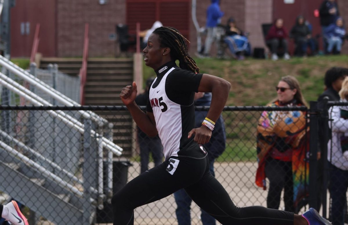 Sprinting, junior Kobi Barton pumps his arms. Barton placed third in the boys varsity 300 Meter Hurdles event at the Rolland Garrison Invitational.